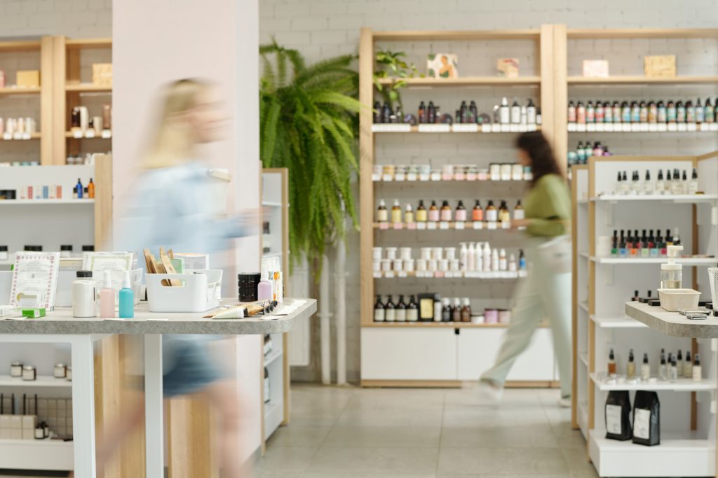 blurry-motion-two-young-women-moving-along-displays-with-self-care-items